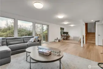 Family room downstairs looking into office area. Sliding doors to lower outside deck. Stairs to upper level.