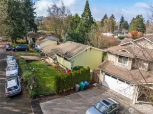Elevated view capturing the home’s position along a quiet residential street with nearby greenery.