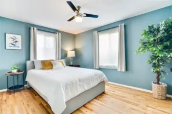 This primary bedroom features natural light from large windows, newer refinished hardwoods and ceiling fan to keep the air from your newer heat pump moving!
