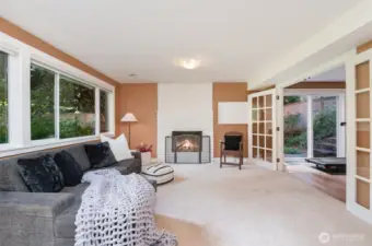Large, lower level living room with fireplace and big window overlooking front yard.