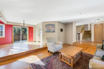 A good look at the formal sunken living room, with the dining area to the left. On the right, stairs lead up to the primary ensuite and two guest bedrooms, plus a full hallway bathroom.