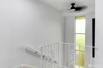 Bright and airy stairwell with vintage inspired railing and unique privacy glass window detail.