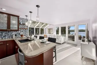 The remodeled kitchen blends effortlessly into the styling of the home with rich cabinet finishes, granite countertops and a  tile backsplash all evoking the natural tones of the water and bordering forest.