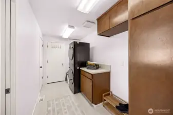 The large utility room with extra storage and pantry closet leads to the main floor 3/4 bath seen in the background and the exterior door to the breezeway and garage for easy loading and unloading.