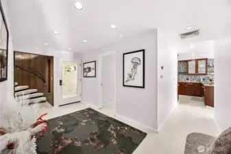 The front entry hall serves as an axis point to all areas of the home.  The classic spiral stair way highlights the unique NW styling of the home. The main floor bedroom sits across from the bath.  Photo from living area.