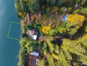 An aerial view of the property highlights the layout of the 1-plus acre lot with a mix of natural and improved landscaping and terraced terrain.  Don't miss the large upper 5 bay storage/shop space ready for boats and toys.