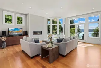 Sunlit living room with expansive Marvin windows that capture the shimmering water views