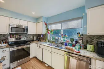 Spacious kitchen overlooking backyard with upgraded cabinets and countertops with newer stainless steel appliances