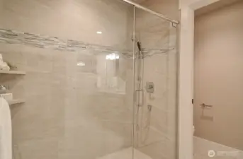 Large tiled shower with glass door in the primary bath.