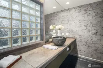 A large glass-block wall welcomes natural light into the main-floor 3/4 bath (the shower is out of frame on the right.)