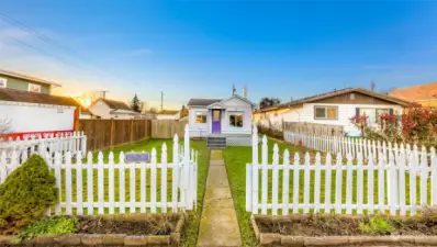 Welcome to 2509 Toledo Street, a charming 1930s cottage in Bellingham’s Roosevelt Neighborhood. This photo showcases the inviting curb appeal with a classic white picket fence, vibrant purple door, and spacious front yard, perfect for outdoor relaxation or gardening. Located on a quiet dead-end street, just steps from the Railroad Trail and local amenities, this home offers both character and convenience.