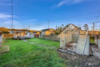 Featuring a greenhouse, this yard offers a great setup for gardening enthusiasts or anyone looking to grow their own produce.