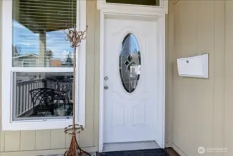 Welcome home to this charming entrance, featuring a classic white front door with an elegant oval window. The entryway is designed to make a great first impression, with a stylish wall-mounted mailbox and a large window that brightens the porch. This inviting space is the perfect introduction to the comfort and style found throughout the home.