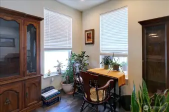 This sunlit nook offers a versatile space with two large windows, creating a bright and inviting atmosphere. It’s perfect for a cozy breakfast area, a productive home office, or a quiet reading spot. The room is framed by rich wooden cabinets, adding a touch of classic elegance and ample storage or display space.
