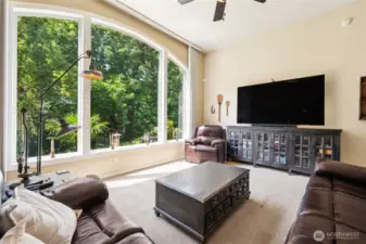 Impressive living room with vaulted ceilings and a stunning wall of windows framing lush greenery.