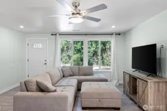 Living room has large vinyl windows, vinyl plank flooring and ceiling fan to keep you cool in the summer.