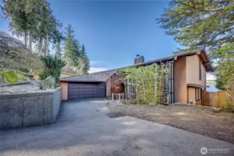 A striking bridge-style entry crosses the serene koi pond, creating a memorable approach to the home.