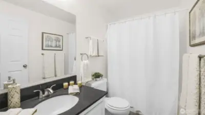 Centrally located full bath with more of the sleek countertops and white shaker cabinetry.