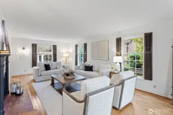 The spacious living room runs the length of the home, and  boasts hardwood floors and picture double-pane windows overlooking park like grounds.