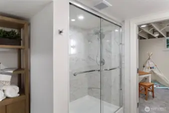 The lower level bath features Carrera design shower surround, 12 X 24 gray tile flooring, Kohler white oak double vanity, chrome fixtures and designer lighting.