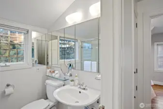 The upstairs full bathroom has marble tile flooring, a tub with tempered glass doors, a new toilet and a beveled glass double-pane window overlooking the gardens.