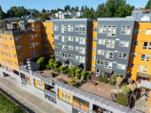 Aerial view of the second-floor community outdoor space, showcasing beautifully landscaped trees and deck access.