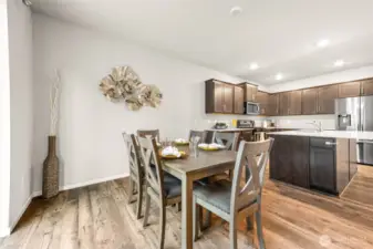 Open-concept kitchen and dining area blends warmth and functionality with rich cabinetry, a large quartz island, and seamless flow—perfect for everyday living and effortless entertaining.