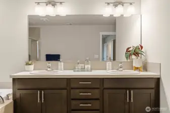 The spa-like ensuite bath features a dual-sink vanity with rich cabinetry, updated lighting, and ample counter space—perfect for busy mornings or relaxed evenings