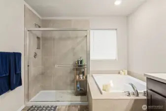 Unwind in the luxurious primary bath featuring a spacious walk-in shower, deep soaking tub, and serene finishes designed for ultimate relaxation