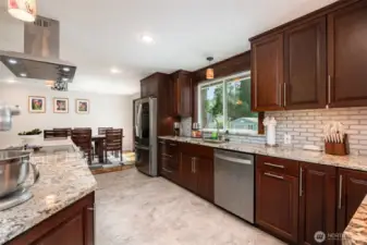 Another angle showcasing all the counter space with granite counters and additional deep wood cabinets.