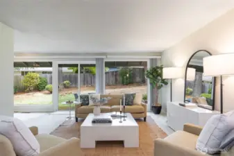 Large living room with floor to ceiling windows looking out at expansive backyard
