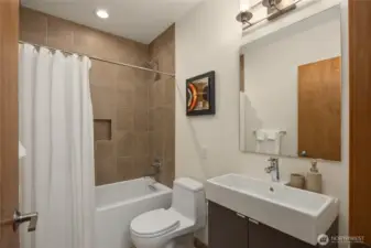 The main hallway bathroom with a tub/shower combo has modern tiles and fixtures.