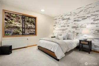 The third bedroom with a wood accent wall and peaceful view out back.