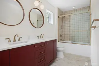 Full upper bath with custom tile work, wood cabinetry and dual sinks.