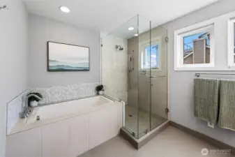 Deep soaking tub and glass enclosed tiled shower.