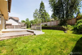 Spacious back yard with retaining wall and fence.