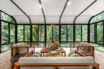 A door off the living area opens into a spectacular 280-square-foot sunroom, surrounded by nature and flooded with natural light.