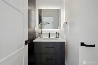 The powder room has a shiplap accent wall, a floating cabinet, and a backlit mirror.