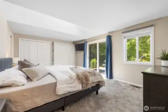 Primary bedroom with two closets, one large skylight with electric blind, and sliding door to deck.