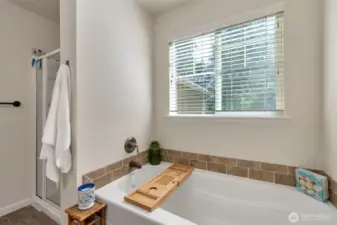 Soaking tub and separate showing in the primary bathroom