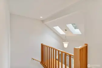 Stair landing showcasing the vaulted ceiling, skylights and beautiful chandelier upon entrance.