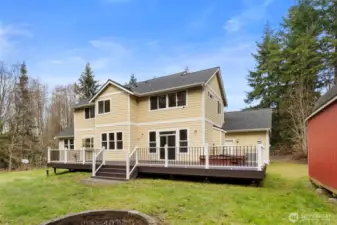 Rear view of this two-story home showcasing an expansive deck and an outdoor shed situated to the right.
