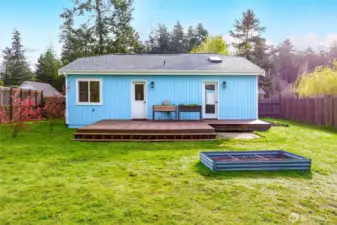 Bright, open backyard with full fencing and raised garden beds ideal for growing vegetables or flowers.