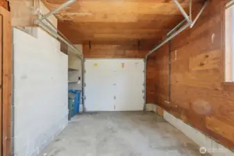 Spacious 1 car garage with added shelving for storage and newer garage door.
