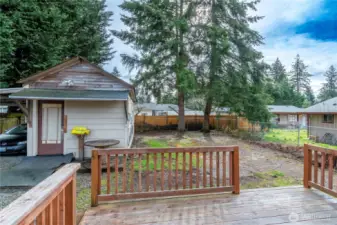 View off wood deck back of home to back yard. Lots of room for toys. Shop/outbuilding with carport attached.