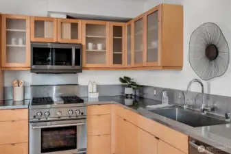 The gourmet kitchen is equipped with commercial-grade appliances, a new microwave, stainless steel counters, and custom cabinetry.