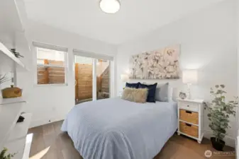 Lower Level Bedroom, with beautiful engineered hardwood flooring, private patio for relaxing with a cup of tea and enjoying nature, built in shelving, spacious room (queen size bed pictured) and large closet