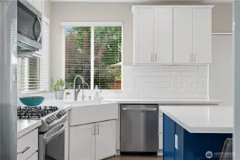 A highly functional kitchen awaits with a premium gas range, spacious farmhouse sink, and a modern stainless steel dishwasher.