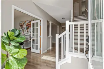 Main level begins with an entryway, leading to a dedicated home office/den with French doors and a staircase to the upper level.