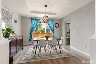 Elegant and inviting dining room defined by stately columns and a tray ceiling with a modern light fixture—ideal for entertaining.